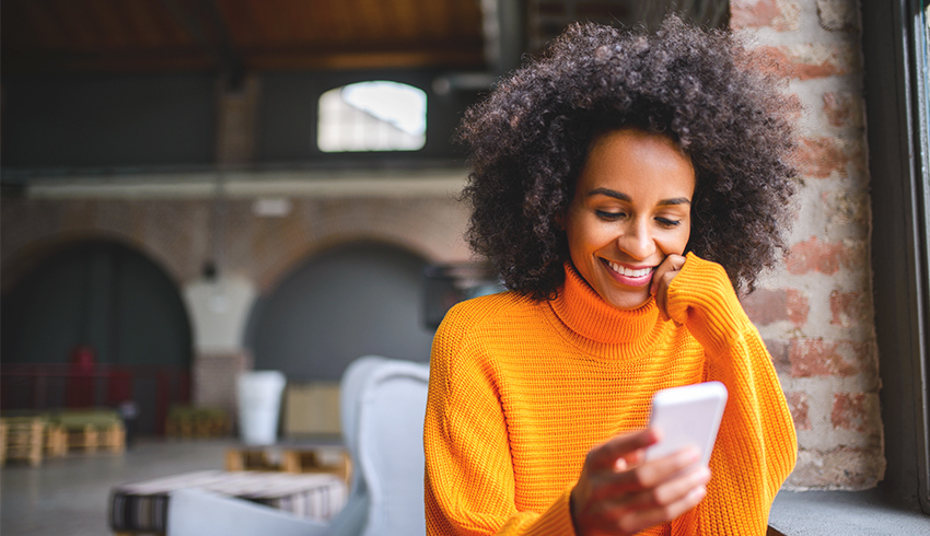A woman looking at a smartphone in an open-concept building